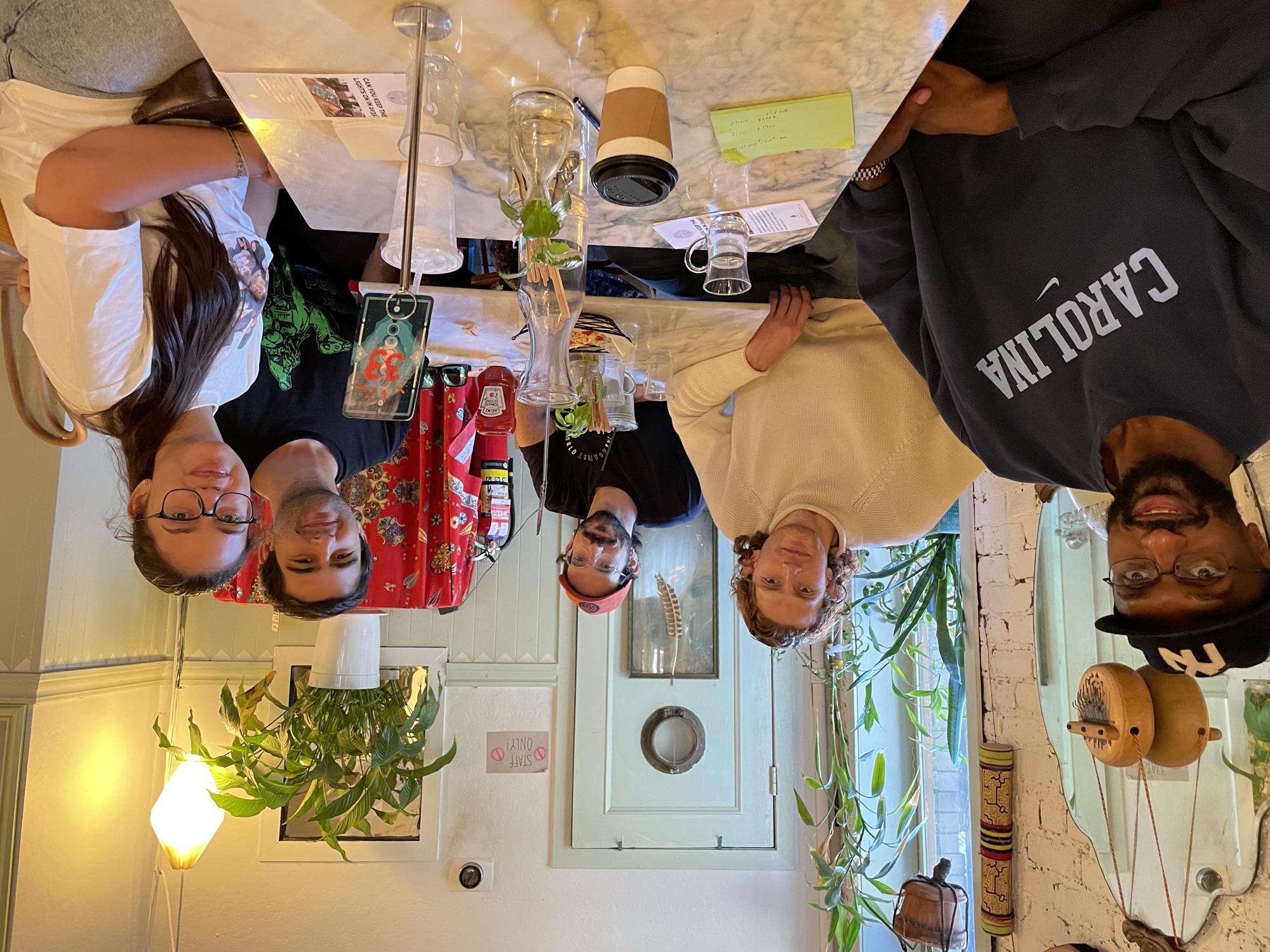 Five walkers around a café table after the walk, notes and coffee on the marble tabletop