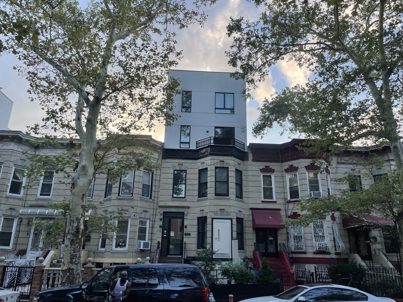 A Bushwick rowhouse with three new floors built on top, rising above its two-story neighbors on the same block